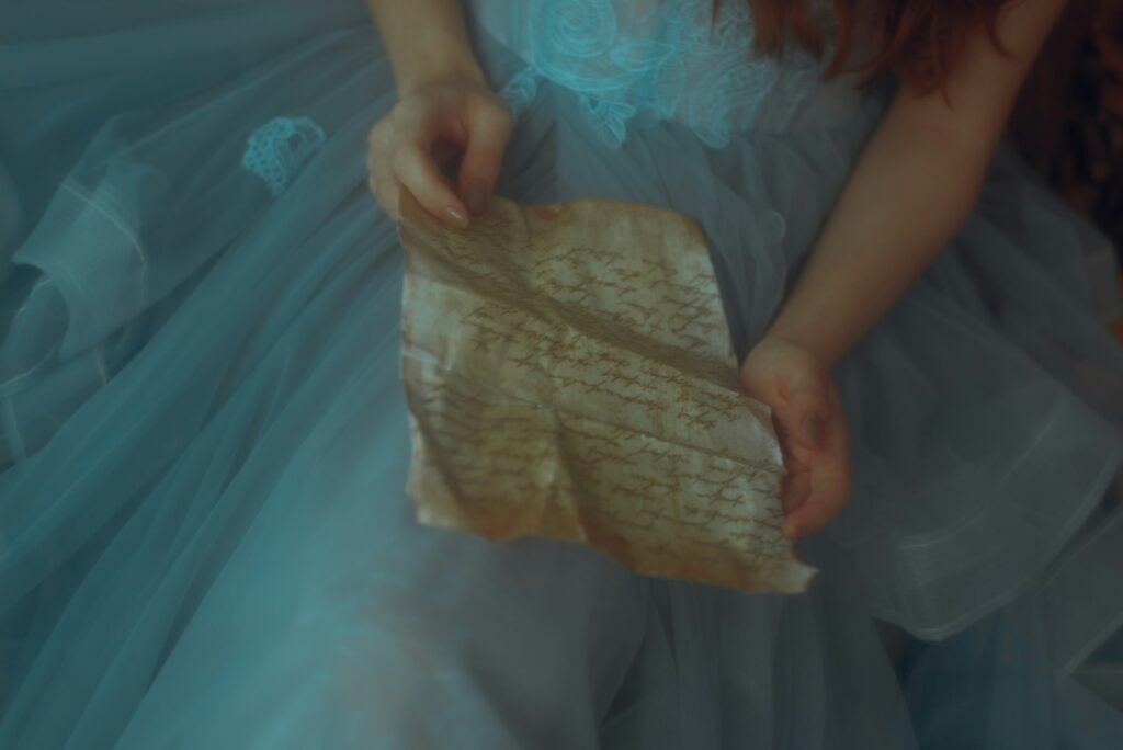women in blue dresss holding scroll with cursive handwriting